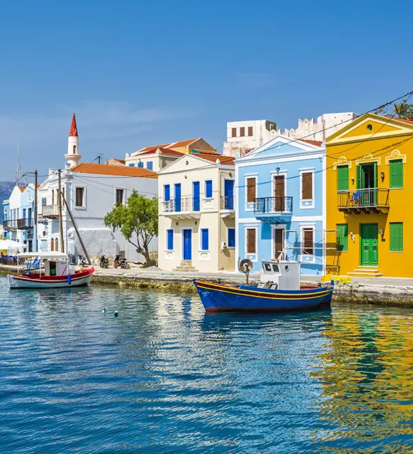Pastel-coloured waterfront houses and a clear bay surrounding Kastellorizo harbour.